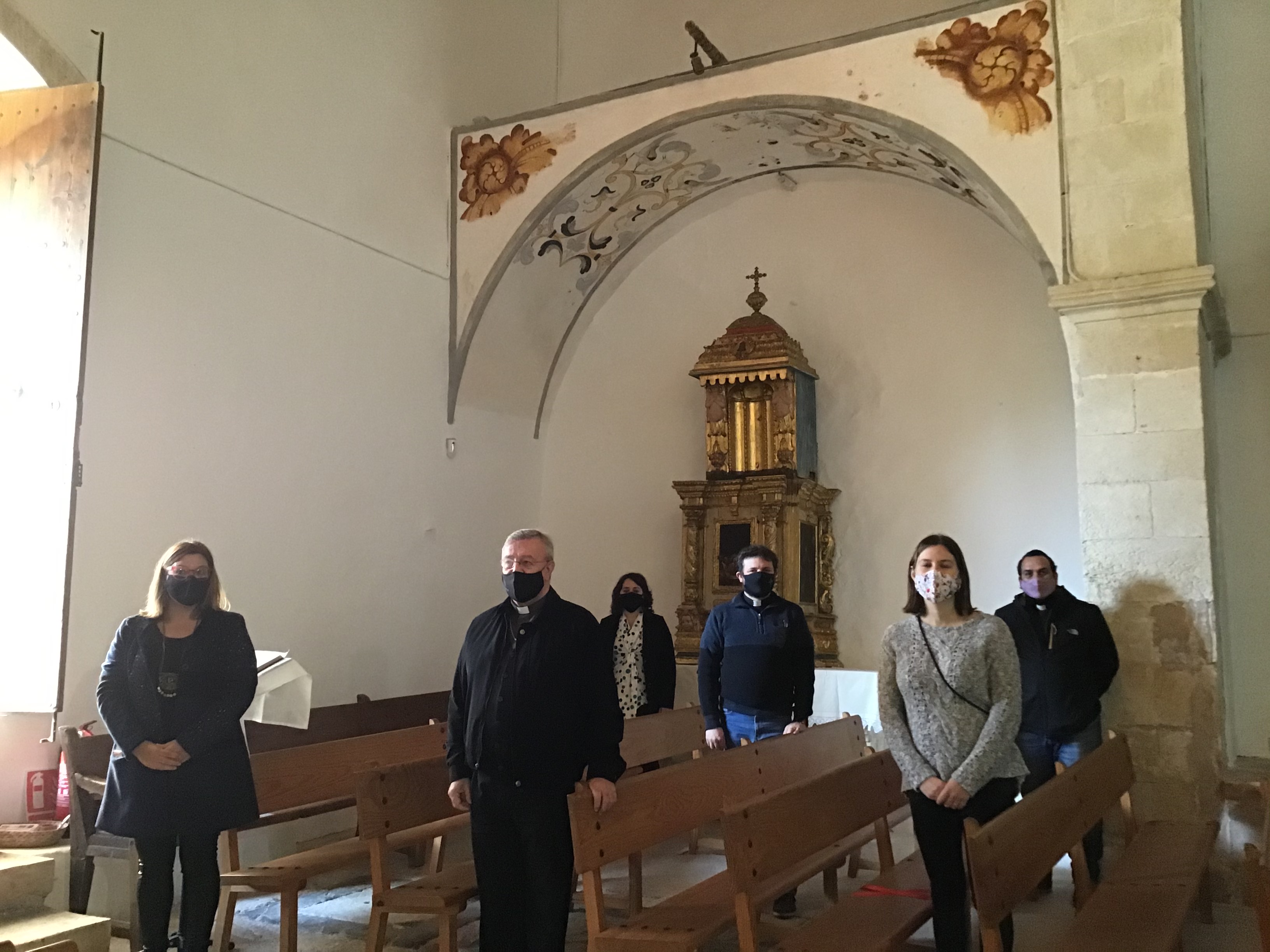 Foto de família davant les pintures murals i el tabernacle de l'oratori de Sant Miquel de Campanet, restaurades gràcies a la col·laboració del Consell i el Bisbat