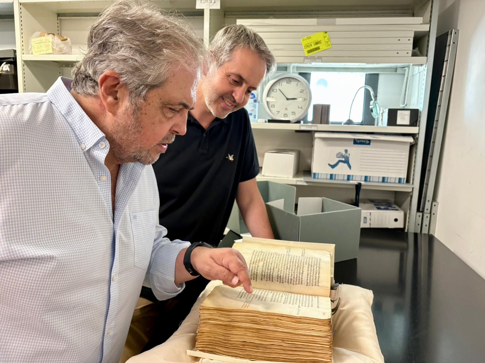 El conseller d'Hisenda, Innovació i Funció Pública, Rafel Bosch, i el responsable de producció d'exposicions i publicacions dels arxius de Montpeller, Pierre-Joan Bernard, observen un llibre.