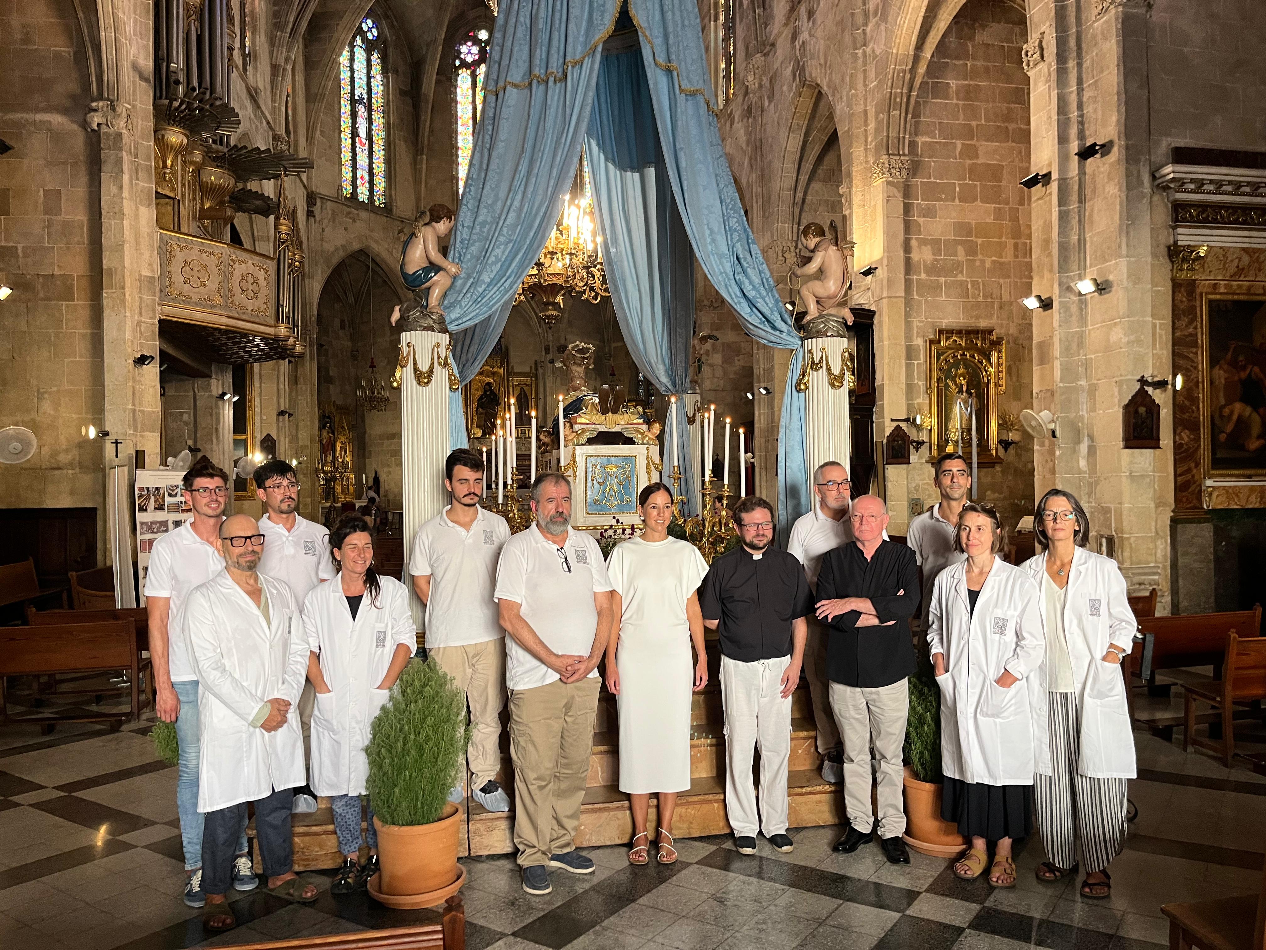 Imagen de la vicepresidenta del Consell de Mallorca y consellera de Cultura y Patrimonio, Antònia Roca; y el vicario episcopal del Patrimonio Histórico y Cultural del Bisbat de Mallorca, Mn. Francesc Vicens con el equipo restaurador.